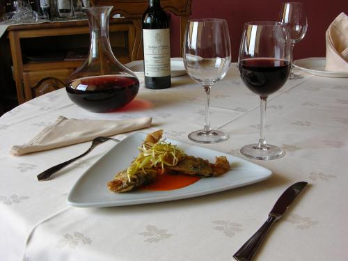 a plate of food on a table with wine glasses at Hotel Rural La Dehesilla in Barajas de Gredos