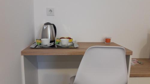 a table with a coffee maker and a chair on it at Airport room's Residence Garden in Velika Gorica