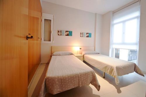 2 camas en una habitación pequeña con ventana en RealRent Marina Real, en Valencia