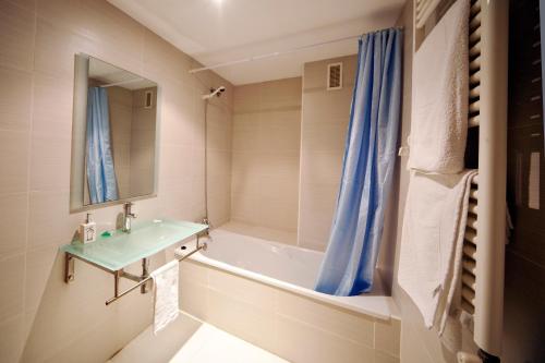 y baño con lavabo, bañera y espejo. en RealRent Marina Real, en Valencia