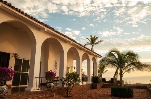a building with arches and palm trees next to the ocean at Rancho Las Cruces in Las Cruces