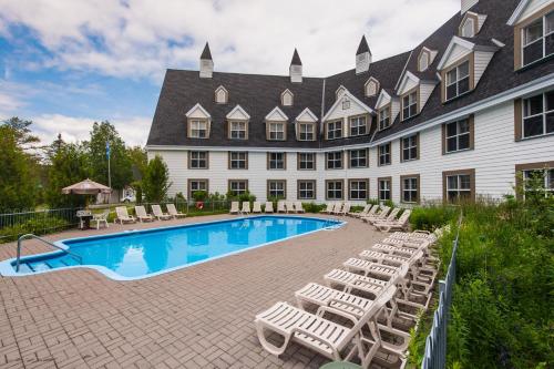 a hotel with a swimming pool and lounge chairs at Gîte du Mont-Albert - Sepaq in Sainte-Anne-des-Monts