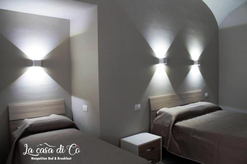 a bedroom with two beds and lights on the wall at B&B La casa di Cò in Naples