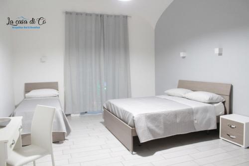 a bedroom with two beds and a table and a chair at B&B La casa di Cò in Naples