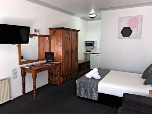 a hotel room with a bed and a desk with a computer at New England Motor Inn in Armidale