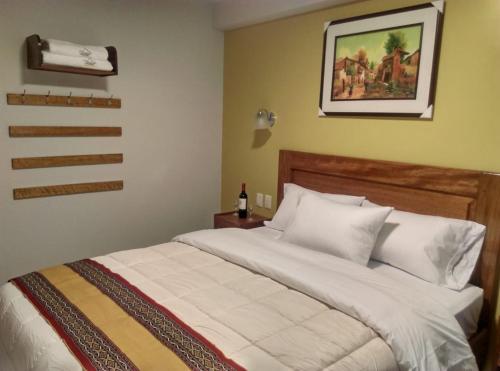 a bed in a bedroom with a picture on the wall at Picos House MachuPicchu in Machu Picchu