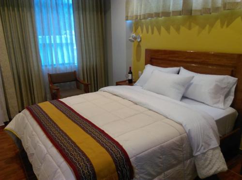 a bedroom with a large white bed and a window at Picos House MachuPicchu in Machu Picchu
