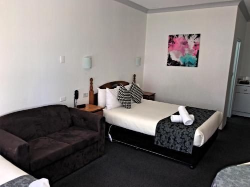 a hotel room with a bed and a couch at New England Motor Inn in Armidale