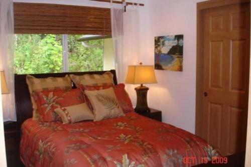a bedroom with a red bed and a window at Bamboo Valley Inn in Haiku