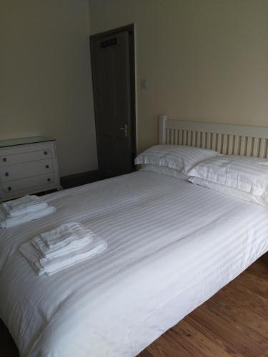 two beds in a bedroom with white sheets and towels at 64 Wardo Avenue in London
