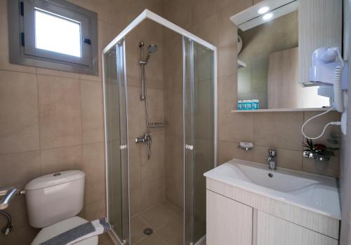 uma casa de banho com um chuveiro, um WC e um lavatório. em Magician's Apartments em Lefkada Town