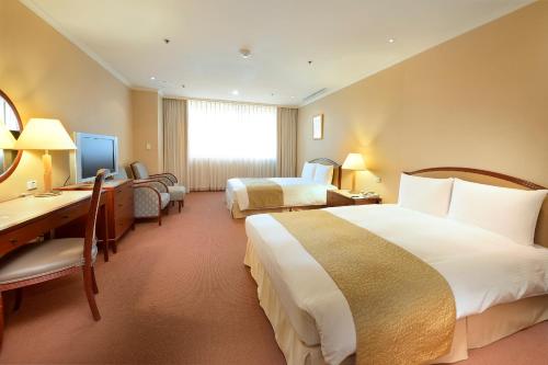 a hotel room with two beds and a desk at Le Midi Hotel Jungli in Zhongli