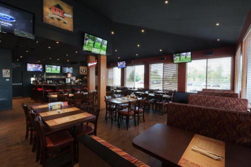 a restaurant with tables and chairs and televisions at N Hôtel Québec in Quebec City