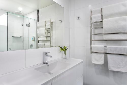 a bathroom with a sink and a mirror and towels at Hamilton Lonsdale Motel in Hamilton