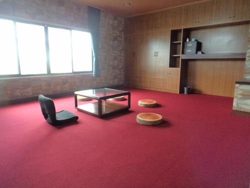 a room with a red carpet and a table and a chair at Konpira House in Kotohira