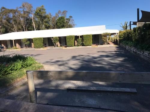 a wooden bench sitting in front of a building at Tea Gardens Motel in Tea Gardens