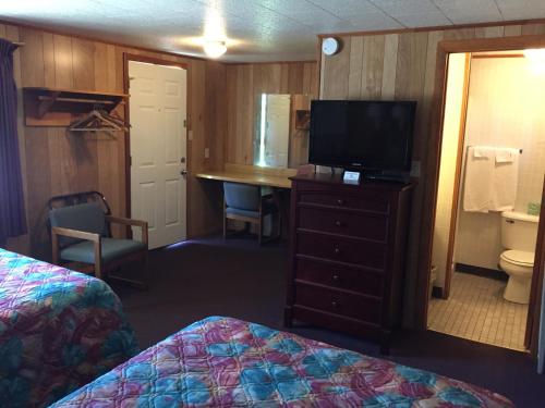 a hotel room with a bed and a desk with a television at Elmwood Motor Lodge in Boscawen