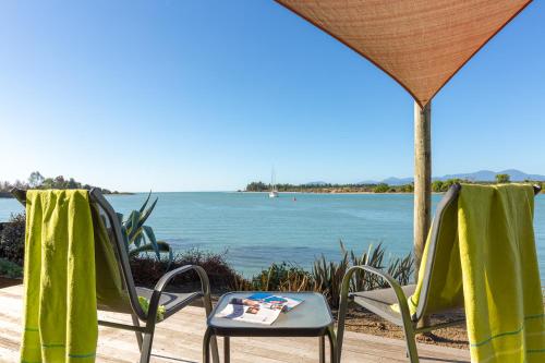 two chairs and a table with a view of the water at Mapua Wharfside Apartments in Mapua