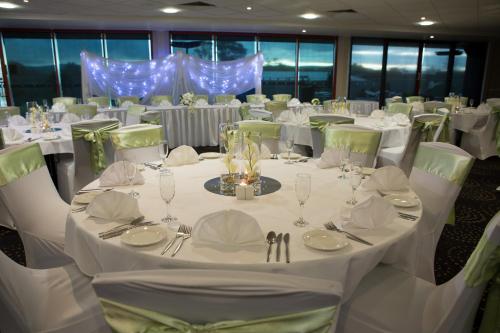a dining room with white tables and chairs with white tablesearcher at Macquarie 4 Star in Warners Bay