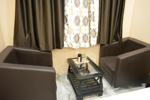 two chairs and a table in a room with curtains at Olive suites in Patna