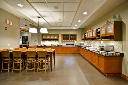 a large kitchen with wooden cabinets and a table and chairs at Hyatt Place Chicago/Naperville/Warrenville in Warrenville