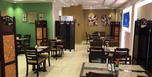 a dining room with tables and chairs and green walls at Holiday Season in Tabuk