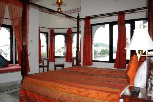 a bedroom with a bed with red curtains and windows at Karohi Haveli - A Heritage Hotel in Udaipur