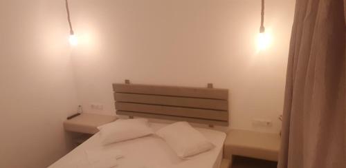 a bedroom with a bed with two pillows and two lights at Pension Verykokkos in Naxos Chora