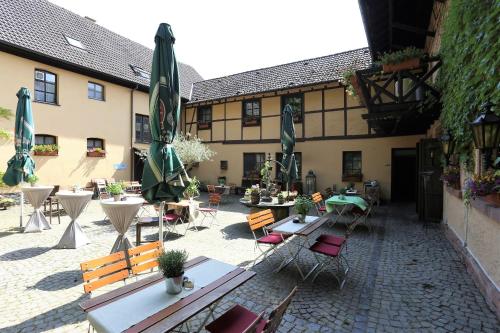 an outdoor courtyard with tables and chairs and umbrellas at Landhotel Burkartsmühle in Hofheim am Taunus