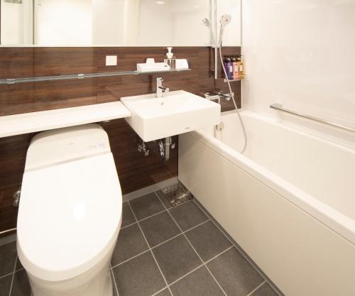 a bathroom with a toilet and a sink and a tub at Hotel Vischio Osaka-JR Hotel Group in Osaka