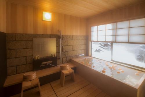 ein Bad mit einer Badewanne und einem Fenster in der Unterkunft Yamanoo in Kanazawa