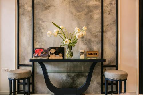 a table with a vase of flowers and two stools at Golden Rooster Hotel in Hanoi