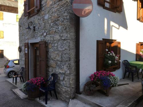 a building with chairs and flowers in front of it at Albergo Meuble Tarandan in Forni di Sopra