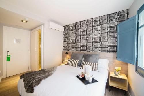 バルセロナにあるBYPILLOW Wanderの白い大型ベッドと壁が備わるベッドルーム1室が備わります。