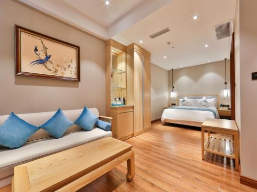 a bedroom with a bed and a couch with blue pillows at Sanya Dadonghai Seaview Hotel in Sanya