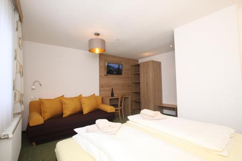 two beds in a room with a couch at Lärchenheim Apartments in Ischgl