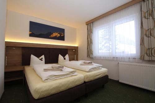a hotel room with two beds and a window at Lärchenheim Apartments in Ischgl