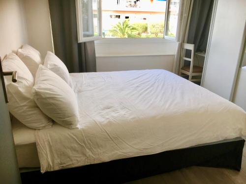 クロ・ド・カーニュにあるCharmant 2 pièces à 50 M de la merの白い枕と窓が備わる白いベッド