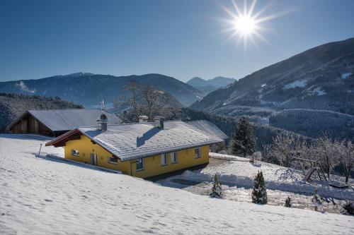 a yellow house in the snow with mountains in the background at Appartament Eichnerhof in Chienes