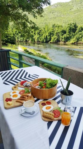 een tafel met eten erop met uitzicht op een rivier bij Aekpailin River Kwai Resort in Kanchanaburi