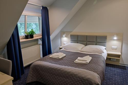 a bedroom with a bed with two towels on it at Hotel Podjadek in Górzno