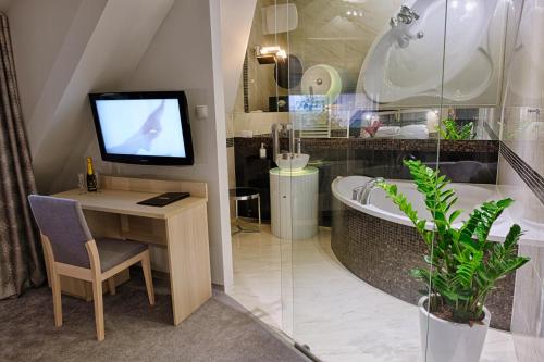 a bathroom with a tub and a television and a desk at Hotel Podjadek in Górzno