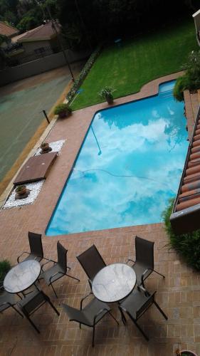 a group of chairs and tables next to a swimming pool at The Bedford View Guest House in Germiston