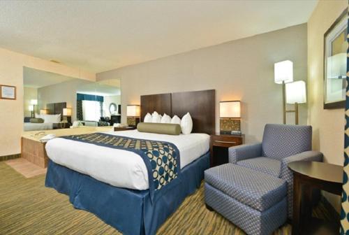 a hotel room with a large bed and a chair at Best Western Plus Coldwater Hotel in Coldwater