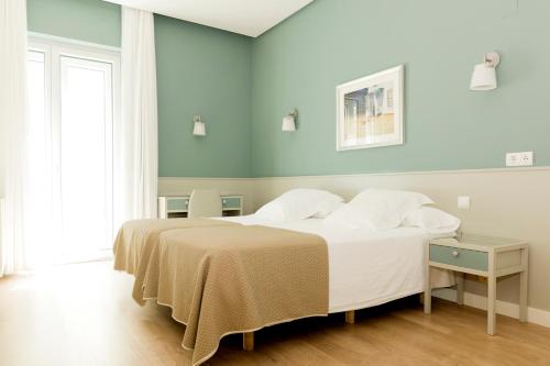 een slaapkamer met een groot bed met witte lakens en kussens bij Hotel Sauce in Zaragoza