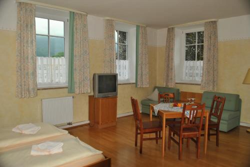 um quarto com uma mesa e cadeiras e uma televisão em Gasthof Kampenwand Aschau em Aschau im Chiemgau