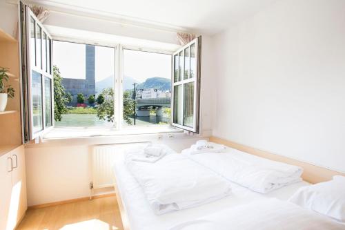 a bedroom with two white beds in front of a window at myNext - Riverside Hotel Salzburg in Salzburg