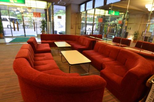 a restaurant with red couches and tables and windows at Shin Kabakawa Kanko Hotel in Takamatsu