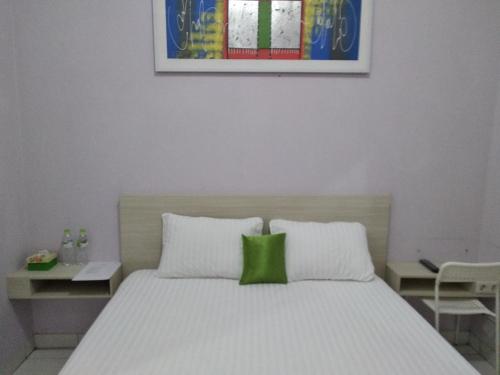 um quarto com uma cama com uma almofada verde em de' GREEN Cibubur em Cibubur
