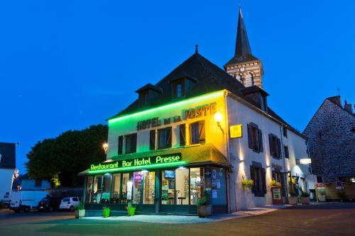 a building with a green sign on a street at Logis Hotel De La Poste in Saint-Sauves- dʼAuvergne